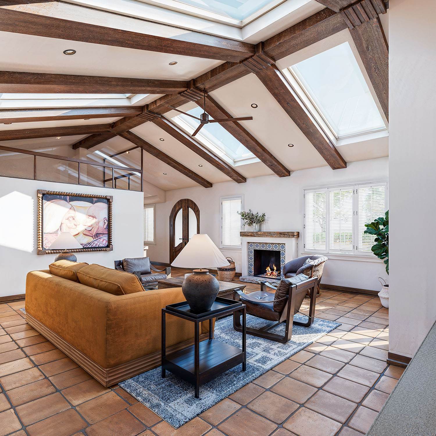 Finished Mediterranean living room with vaulted beamed ceiling, skylights, terra-cotta floors and a tiled fireplace — Mediterranean Estate remodel, Pasadena, by Vividly Built