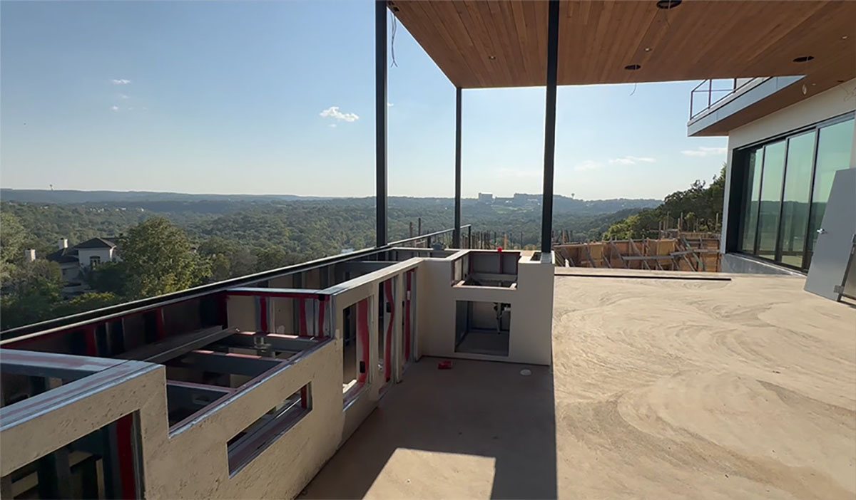 The same balcony during construction — framed outdoor kitchen, bare concrete slab and steel columns, canyon view beyond — Hollywood Hills Residence, Los Angeles